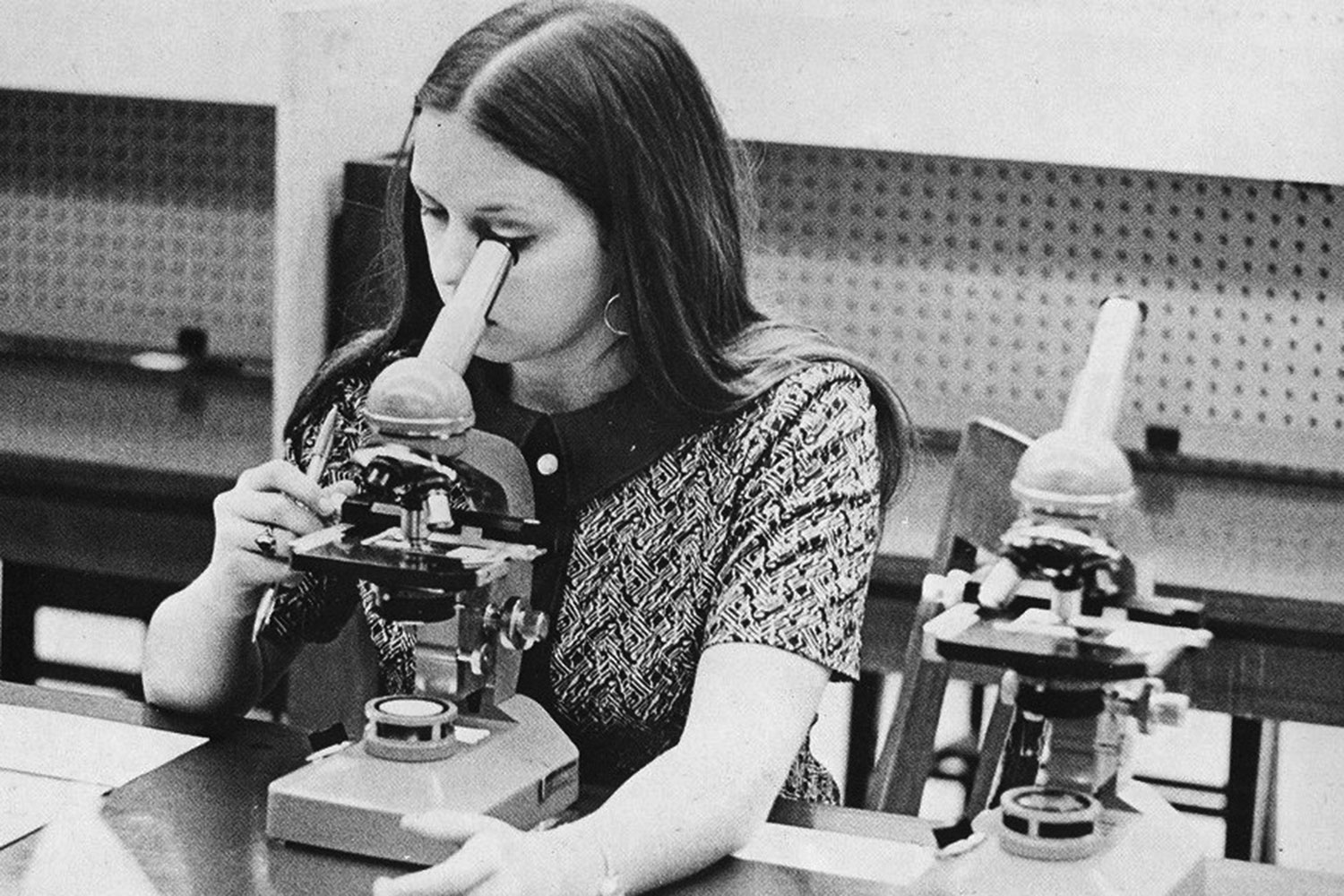 a female student looks through a microscope