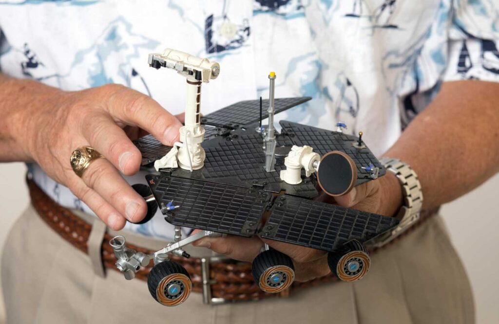 Close up of Hap McSween's hands holding a model of the Mars Opportunity rover