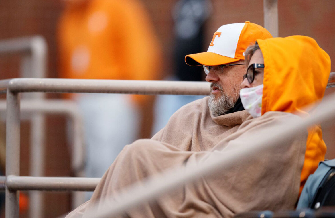 Travis Exum and his wife sit in the stands draped in a blanket, watching the Vol baseball team