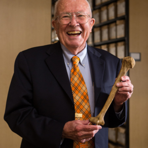 Bill Bass smiles and holds a human long bone