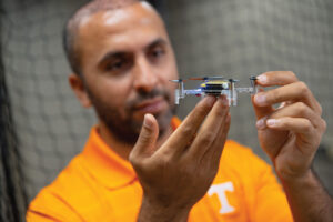A student holds up a tiny drone.