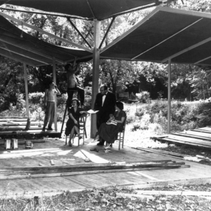 In this historical photo, workers hang shading in the outdoor Carousel theater while actors rehearse.