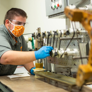 Researcher Josh Crabtree strings carbon fiber through a machine in the lab. 