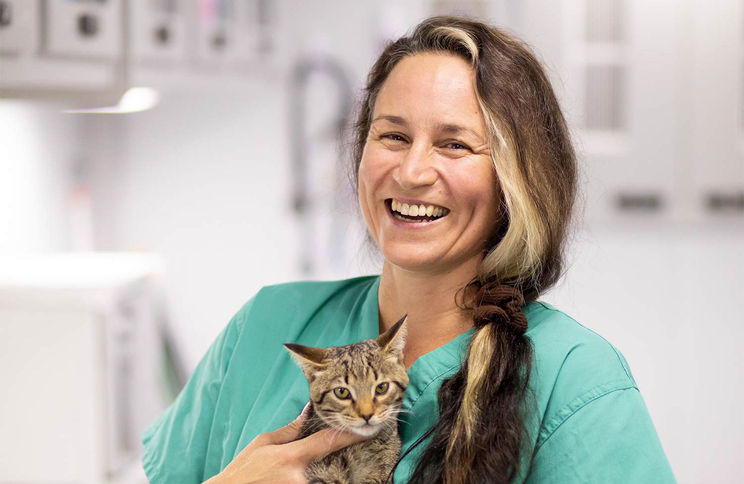 A smiling Jennifer Weisent holding a gray tabby cat.