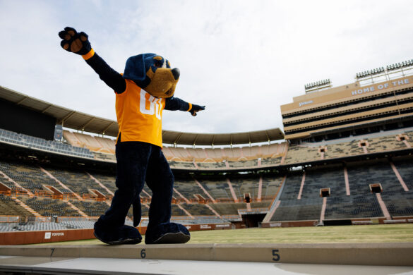 Mascot Smokey walks with his arms out as if he were balancing on a beam