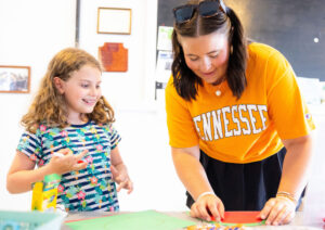 A happy elementary student works with her teacher on a project